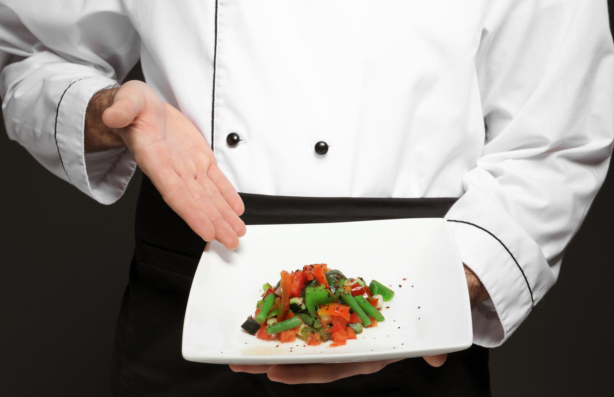 Chef demonstrating a plated dish in a calm studio